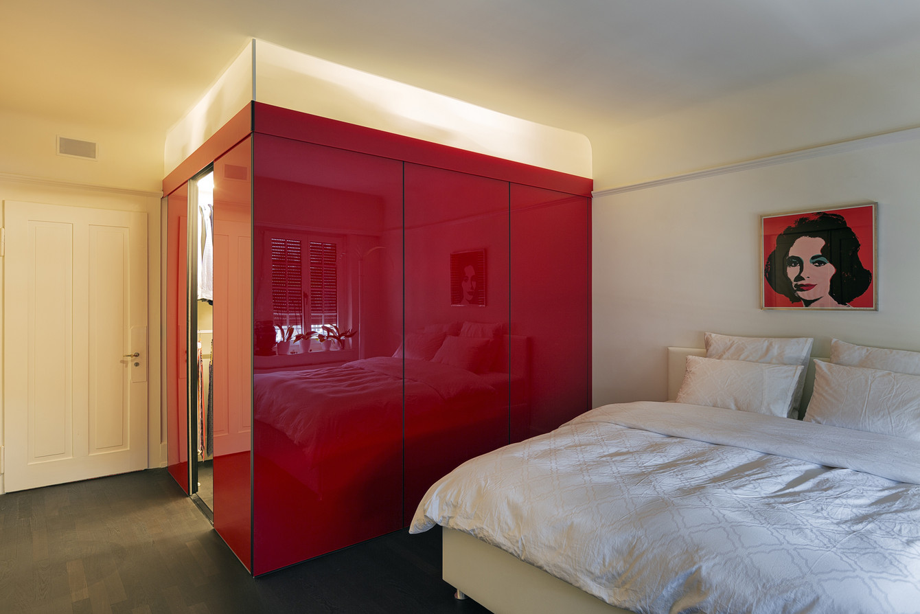 Kubus im Schlafzimmer - dominant in hochrotem Acrylglas gehalten mit sichtbarem Beleuchtungsbalken oben zur Decke 