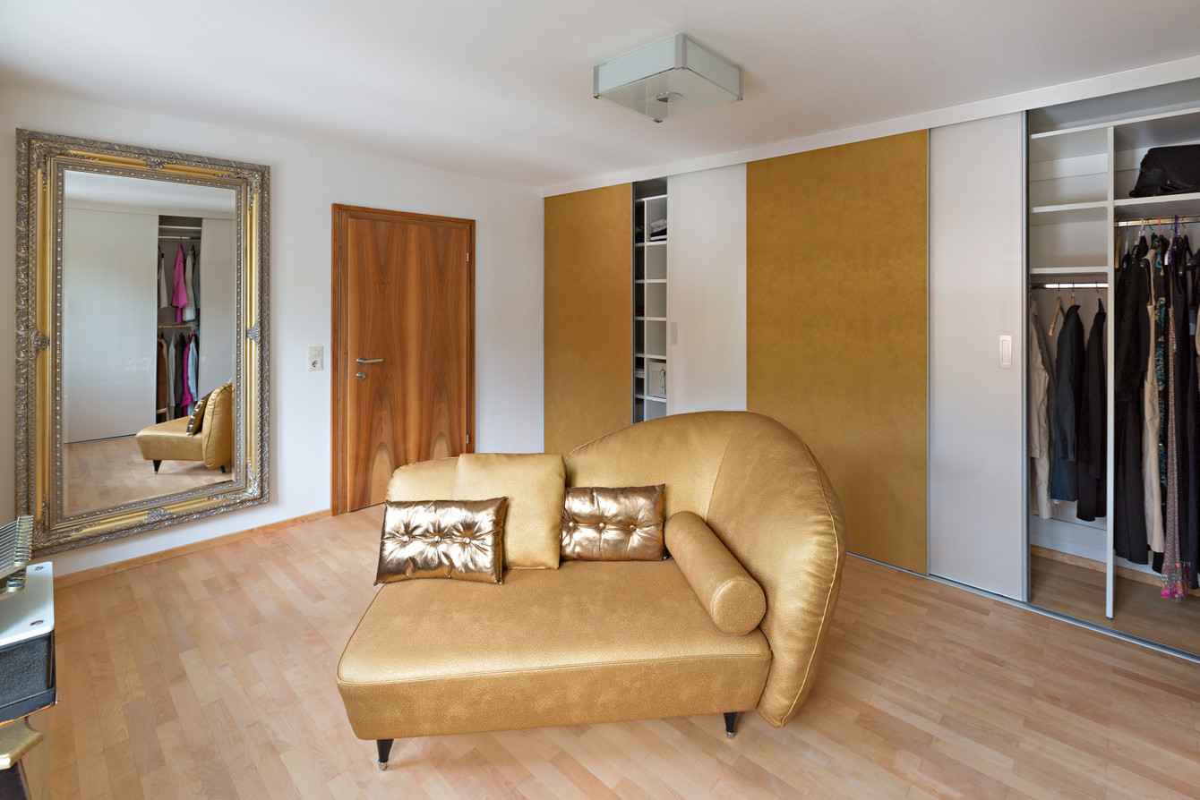 Ankleidezimmer mit goldener Couch, Goldrandspiegel und Leder in der Farbe Gold als Schiebetürfüllung