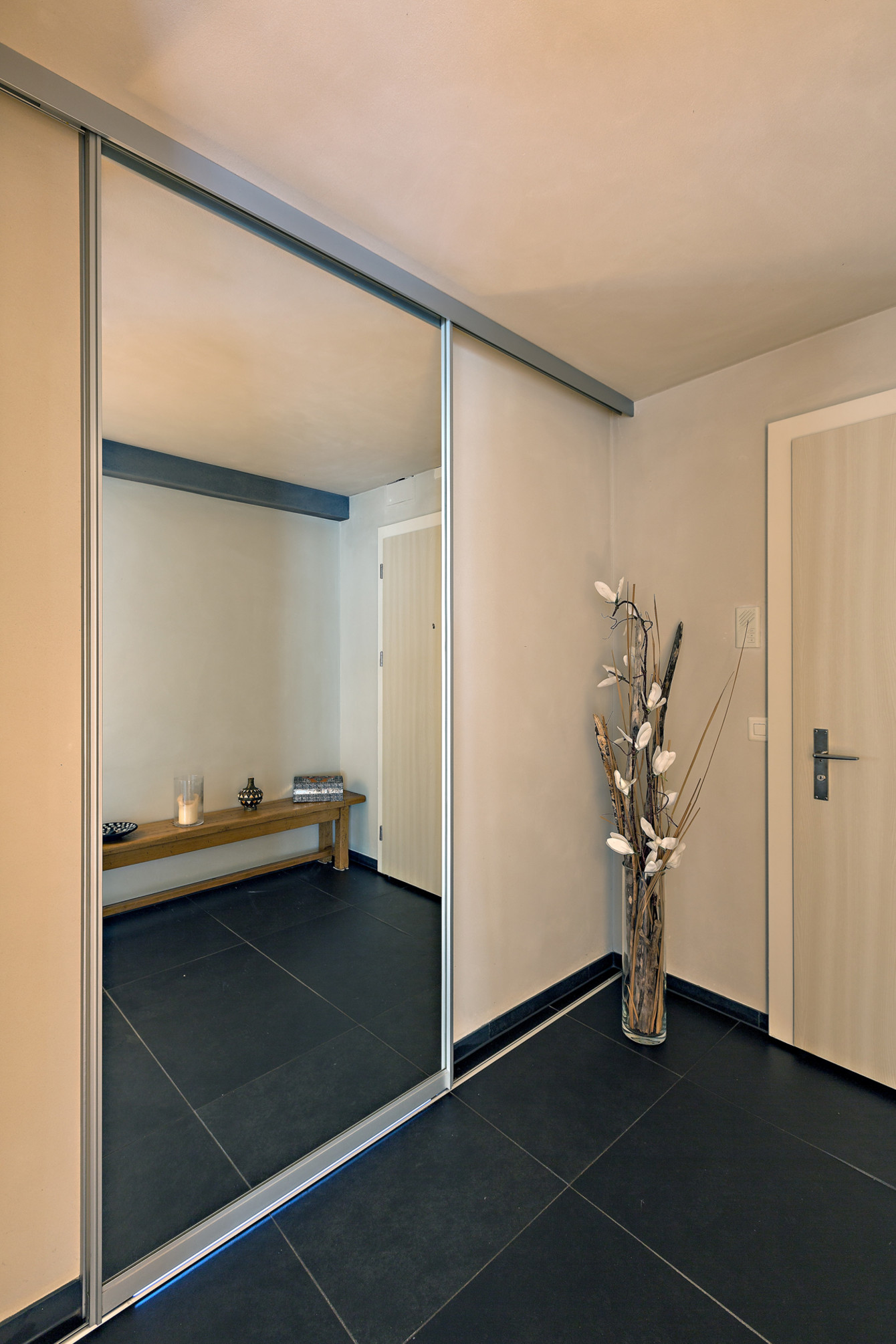 Der übergroße Spiegel verbirgt den Eingang ins Bad - ausgeführt als bewegliche Schiebetür