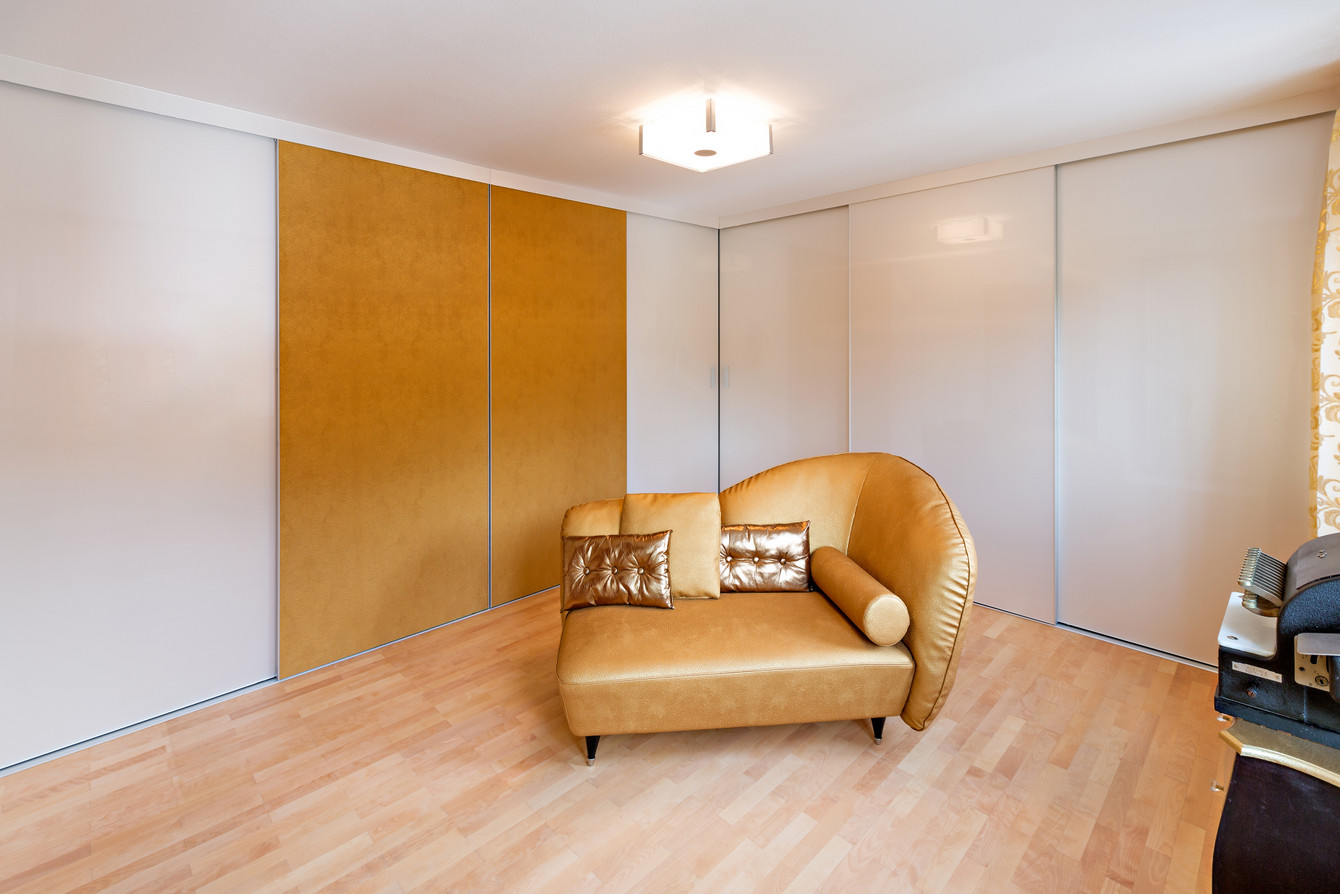 Schrankzimmer mit Schiebetürschränken über Eck - dekorative Füllung der Schiebetüren in Lederoptik gold