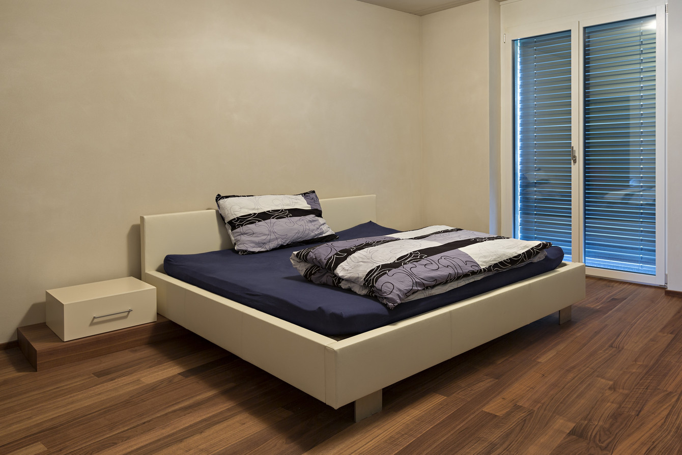 Doppelbett - bezogen mit weissem Leder und dekorative Nachtkästchen auf Holzsockel aufgegesetzt 