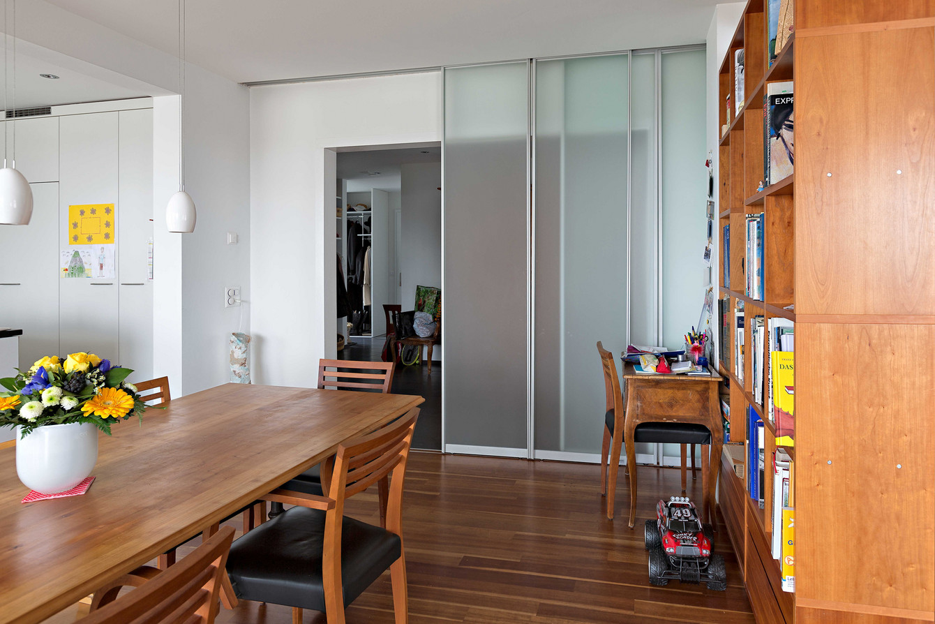 Transparente Trennwand mit vier Schiebetüren als Durchgang vom Gang in die Küche 