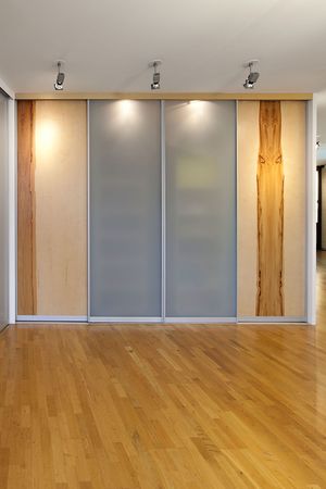 Schiebetürenfront in Glas mittig, eingerahmt von zwei Holztüren mit Baumstruktur